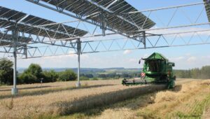 Solarmodule über einem Feld, darunter fährst ein Mähdrescher